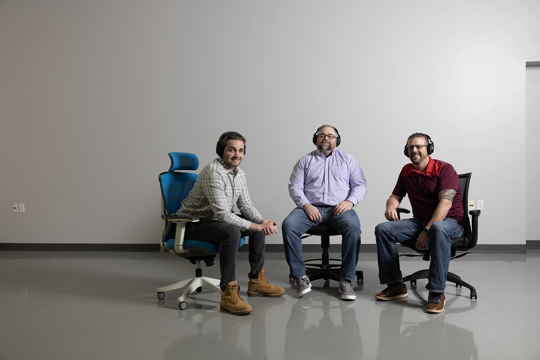 El equipo de soporte técnico de Code Blue posa en grupo sentado en sillas rodantes con los auriculares puestos.
